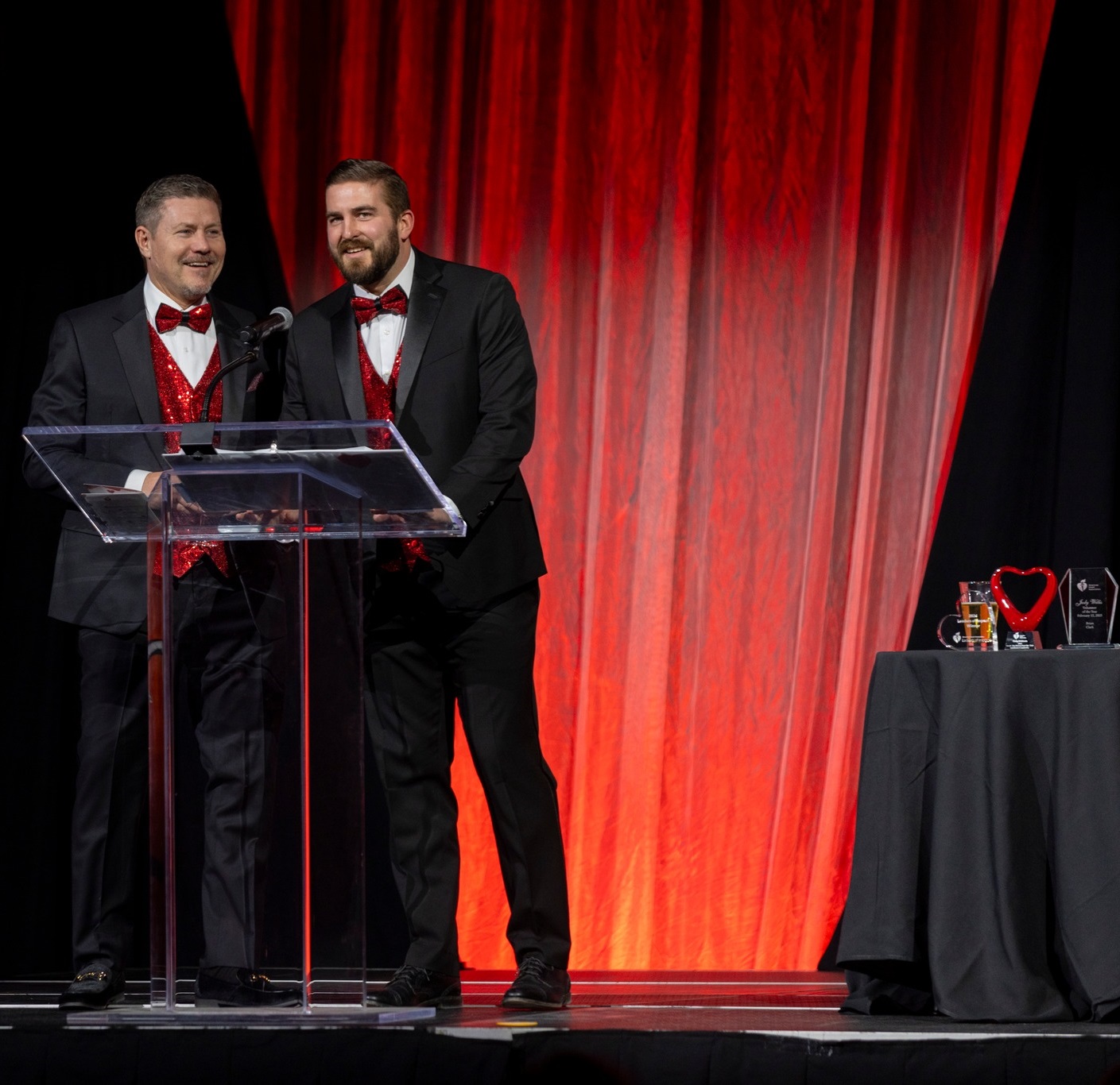 Two men at the podium with awards displayed behind them.